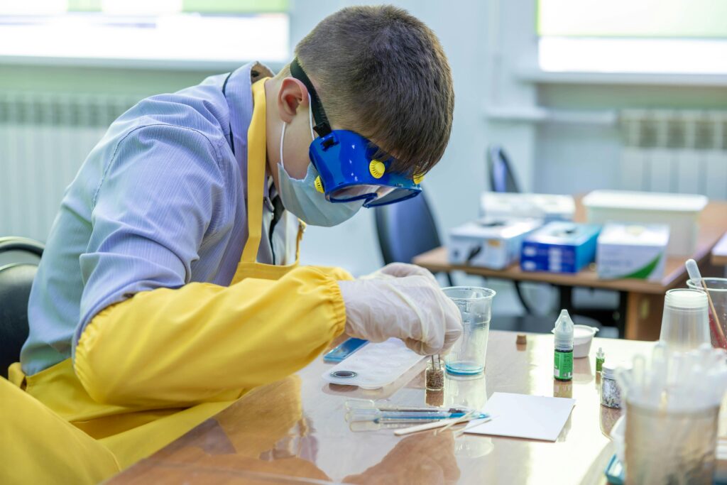 Young student in protective gear performing a chemistry experiment in a laboratory setting.